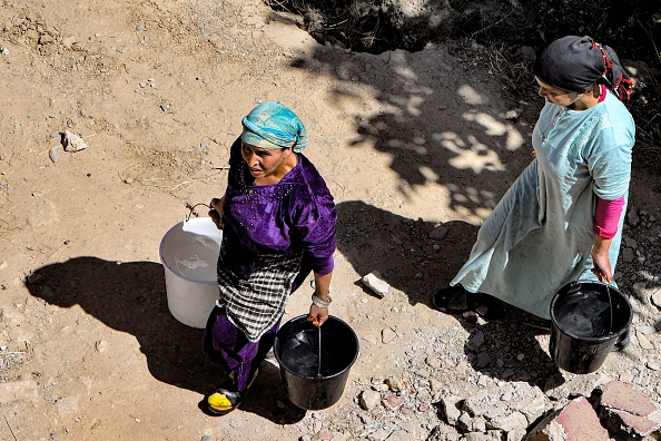 Des femmes marchent avec des seaux d'eau dans le village d'Ineghede, touché par le tremblement de terre dans la province d'al-Haouz, dans le Haut Atlas du Maroc central, le 12 septembre 2023.  (FETHI BELAID/AFP via Getty Images)