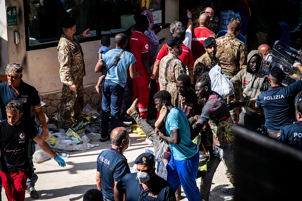 Un migrant reçoit de l'aide devant la porte du centre opérationnel appelé « Hotspot » sur l'île italienne de Lampedusa, le 14 septembre 2023. (Photo ALESSANDRO SERRANO/AFP via Getty Images)