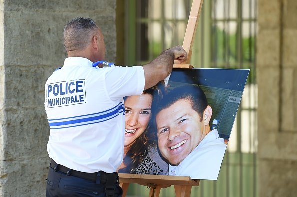 Un policier décroche la photo du couple de policiers Jean-Baptiste Salvaing et Jessica Schneider qui ont été tués devant leur domicile à Magnanville en 2016. (Photo SYLVAIN THOMAS/AFP via Getty Images)