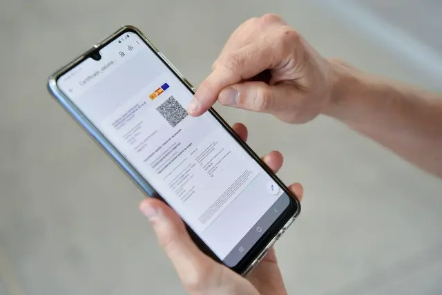 Une femme vérifie son certificat Covid numérique de l'UE sur son téléphone portable à l'aéroport El Prat de Barcelone, le 1er juillet 2021. (Pau Barrena/AFP via Getty Images)