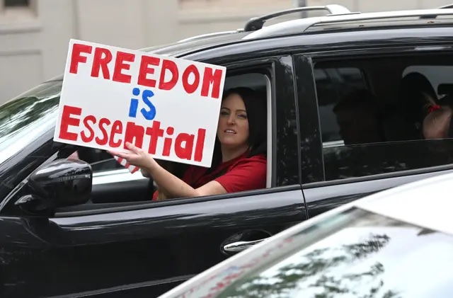 "La liberté est essentielle". Une automobiliste brandit une pancarte alors que des centaines de personnes se rassemblent pour protester contre les mesures de confinement, à Sacramento (Californie), le 20 avril 2020. (Josh Edelson/AFP via Getty Images)
