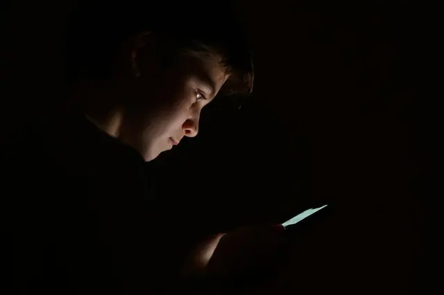 Un adolescent regarde l'écran de son téléphone portable à Londres le 17 janvier 2023. (Leon Neal/Getty Images)
