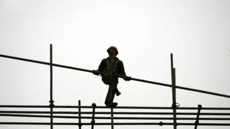 Un travailleur migrant monte des échafaudages sur un chantier de construction dans la municipalité de Chongqing, en Chine, le 13 janvier 2007. (China Photos/Getty Images)