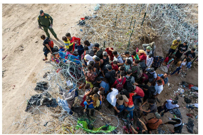 Un agent de la patrouille frontalière américaine observe les migrants qui entrent aux États-Unis après avoir traversé le Rio Grande depuis le Mexique, à Eagle Pass, au Texas, le 30 septembre 2023. (John Moore/Getty Images)