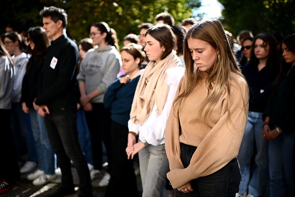 Des lycéens se recueillent pendant une minute de silence en hommage aux professeurs Samuel Paty et Dominique Bernard. (Photo CHRISTOPHE ARCHAMBAULT/AFP via Getty Images)