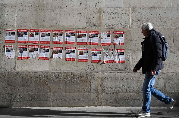 Un homme passe devant des affiches montrant des Israéliens récemment enlevés par les militants du Hamas, dans le centre de Paris, le 27 octobre 2023.   (STEFANO RELLANDINI/AFP via Getty Images)