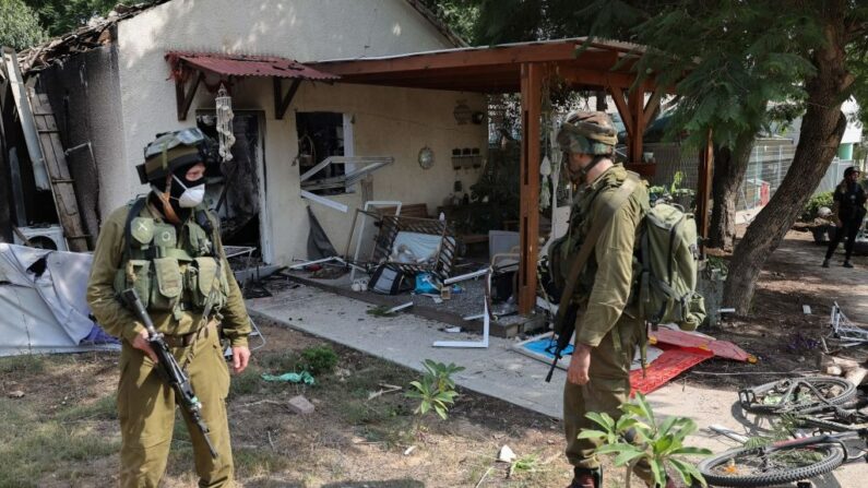 Des soldats israéliens inspectent les dégâts causés par les tirs de roquettes depuis la bande de Gaza dans le kibboutz de Kfar Aza, au sud d'Israël, à la frontière avec le territoire palestinien, le 10 octobre 2023. (JACK GUEZ/AFP via Getty Images)