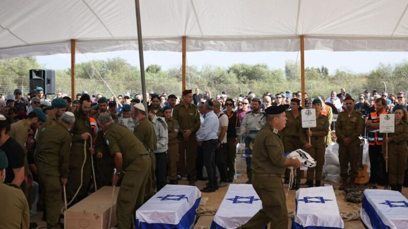 Des personnes se recueillent devant les cercueils des cinq membres de la famille Kutz tués par des terroristes palestiniens dans leur kibboutz de Kfar Aza, lors de leurs funérailles dans la ville de Gan Yavne, dans le centre d'Israël, le 17 octobre 2023. (Oren Ziv/AFP via Getty Images)