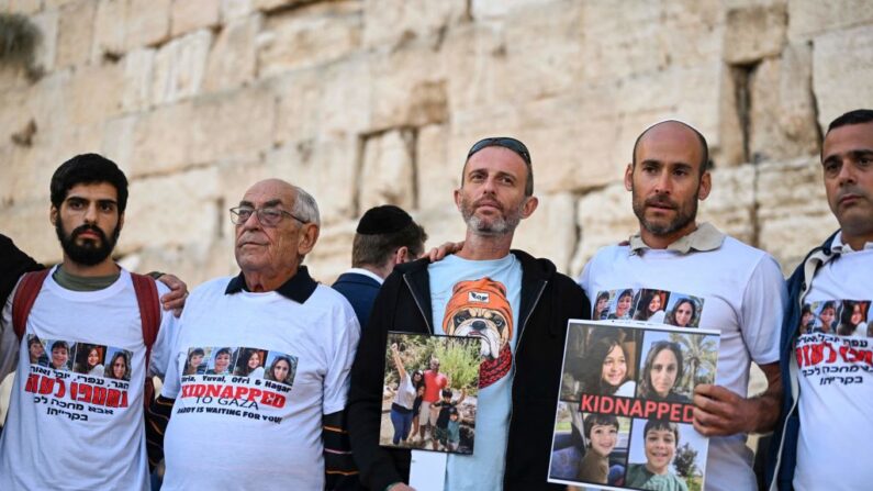 Des parents d'Israéliens disparus soulèvent les portraits de leurs proches devant le Mur occidental lors d'une journée de prière dans la vieille ville de Jérusalem, le 19 octobre 2023. (Photo YURI CORTEZ/AFP via Getty Images)