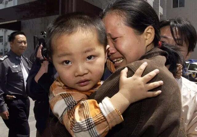 Une femme pleure en retrouvant son fils, l'un des enfants récupérés d'un groupe de trafiquants en Chine centrale, à Zhengzhou, dans la province du Henan, le 6 mai 2005. (STR/AFP via Getty Images)