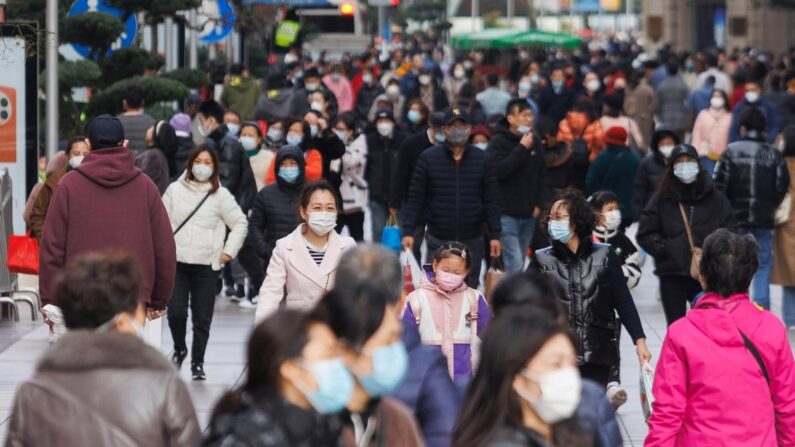 Des personnes portent des masques de protection et marchent sur la route de Nanjing à Shanghai, en Chine, le 11 décembre 2022. (Hu Chengwei/Getty Images)