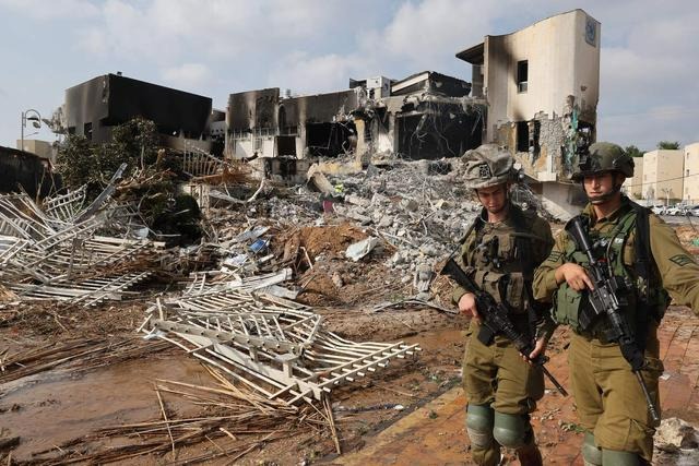 Des soldats marchent devant un poste de police israélien qui a été endommagé lors des combats menés pour déloger les militants du Hamas qui se trouvaient à l'intérieur, le 8 octobre 2023. Le 8 octobre. (Jack Guez/AFP via Getty Images)