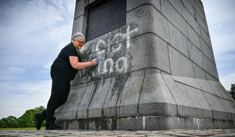 Une personne nettoye la statue de Robert Bruce, taguée avec les inscriptions "roi raciste" à Bannockburn, en Ecosse, le 12 juin 2020; (Jeff J. Mitchell/Getty Images)
