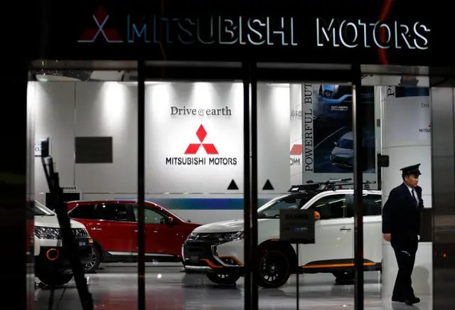 Un agent de sécurité passe devant un véhicule utilitaire sport hybride rechargeable Outlander de Mitsubishi Motors exposé au siège de l'entreprise à Tokyo, le 20 avril 2016. (Tomohiro Ohsumi/Getty Images)