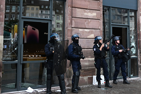 Des policiers à côté de la façade d'un Apple Store endommagé place Kleber, à Strasbourg, le 30 juin 2023, alors que des émeutes et des incidents ont éclaté après la mort de Nahel. (Photo PATRICK HERTZOG/AFP via Getty Images)