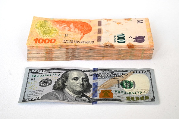 Cette photo montre un billet de 100 dollars américains et son équivalent en pesos argentins - 100 000 pour le " dollar bleu " non officiel du marché parallèle. (Photo : LUIS ROBAYO/AFP via Getty Images)