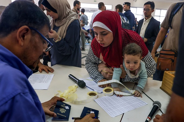 Des civils montrent leurs documents alors que des Palestiniens et des étrangers à double nationalité se préparent à traverser le poste frontière de Rafah avec l'Égypte, dans le sud de la bande de Gaza, le 2 novembre 2023. (Photo SAID KHATIB/AFP via Getty Images)