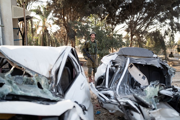 Un soldat de l'armée israélienne inspecte quelques maisons brûlées dans le kibboutz Kfar Aza, où les militants du Hamas ont massacré et kidnappé les résidents le 7 octobre 2023. (Photo DIMA VAZINOVICH/Middle East Images/AFP via Getty Images)