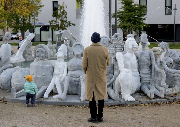 Un homme et un enfant regardent la sculpture intitulée «  WirWasser Brunnen » (« Notre fontaine d'eau ») créée par le groupe d'artistes Gelatin à Vienne, en Autriche. (Photo JOE KLAMAR/AFP via Getty Images)