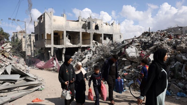 Des familles palestiniennes passent devant des bâtiments détruits à Bureij, dans le centre de la bande de Gaza, le 14 novembre 2023. (Photo MOHAMMED ABED/AFP via Getty Images)