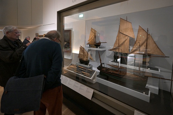 Des personnes regardent des modèles de bateaux de pêche anciens exposés au musée de la Marine, à Paris, le 16 novembre 2023. (Photo MIGUEL MEDINA/AFP via Getty Images)