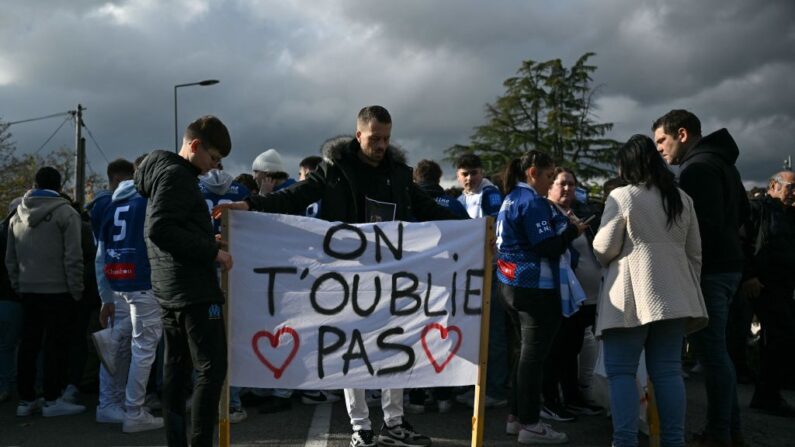Un homme se tient derrière une banderole « On ne t'oublie pas » à Romans-sur-Isere, dans le sud-est de la France, le 22 novembre 2023, avant le départ d'une  « Marche Blanche » en hommage à Thomas. (Photo OLIVIER CHASSIGNOLE/AFP via Getty Images)