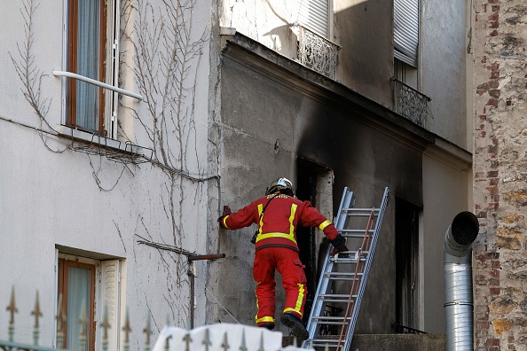 Un pompier inspecte une fenêtre brûlée après qu'un incendie se soit déclaré dans la nuit, à Stains, le 25 novembre 2023. (Photo GEOFFROY VAN DER HASSELT/AFP via Getty Images)