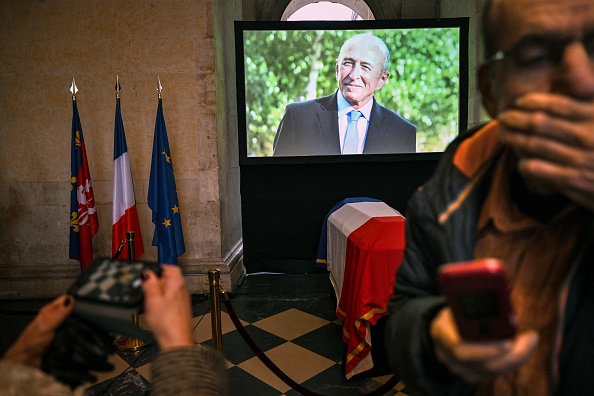 Une photographie montre le portrait apparaissant sur un écran et le cercueil drapé du drapeau de l'ancien maire de Lyon et ancien ministre de l'Intérieur, Gérard Collomb. (Photo OLIVIER CHASSIGNOLE/AFP via Getty Images)