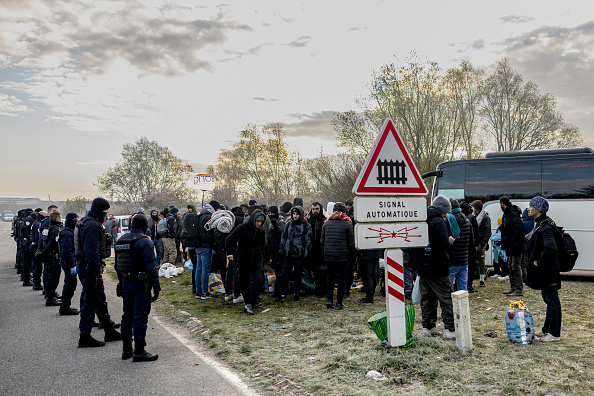 Des migrants sont encerclés par la police nationale alors qu'ils attendent de monter dans un bus pour des centres d'accueil. (Photo SAMEER AL-DOUMY/AFP via Getty Images)