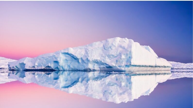Coucher de soleil en Antarctique : un iceberg se reflète dans l'eau.