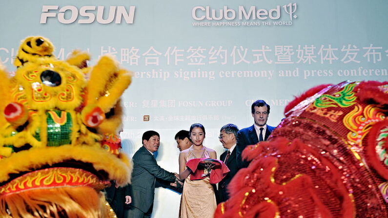 Henry Giscard d'Estaing (à droite), président-directeur général du Club Med, observe une danse traditionnelle chinoise du lion lors de la cérémonie de signature d'un accord de partenariat stratégique entre la société d'investissement chinoise Fosun et le groupe de loisirs français Club Med à Shanghai le 17 juin 2010.   (Photo de PHILIPPE LOPEZ/AFP via Getty Images)