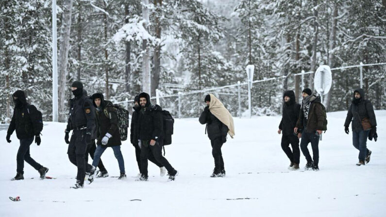 Des gardes-frontières finlandais escortent des migrants à leur arrivée au poste-frontière Raja-Jooseppi à Inari, dans le nord de la Finlande, le 25 novembre 2023. (Photo: EMMI KORHONEN/Lehtikuva/AFP via Getty Images)
