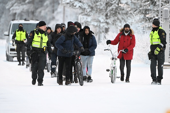 Des gardes-frontières finlandais escortent des migrants au poste-frontière international de Salla, en Finlande, le 23 novembre 2023. (Photo JUSSI NUKARI/Lehtikuva/AFP via Getty Images)