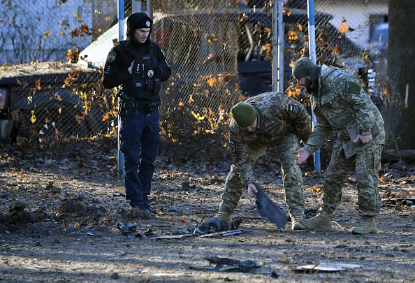 La police ukrainienne et des experts militaires collectent des fragments d'un drone russe abattu près d'un cratère dans une cour au milieu d'immeubles résidentiels à Kiev, le 25 novembre 2023. (Photo SERGEI SUPINSKY/AFP via Getty Images)