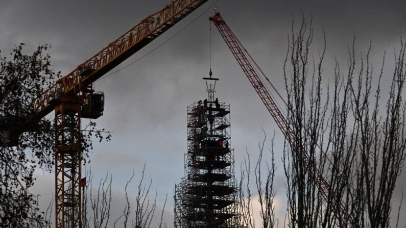 Des ouvriers placent la croix au sommet de la flèche pendant les travaux de reconstruction de la cathédrale Notre-Dame de Paris, sur l'île de la Cité à Paris, le 6 décembre 2023. (Crédit photo Miguel MEDINA / AFP)