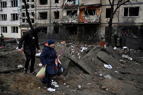 Des personnes passent devant un immeuble résidentiel endommagé à la suite d'un tir de missile à Kiev le 13 décembre 2023. (Photo SERGEI CHUZAVKOV/AFP via Getty Images)