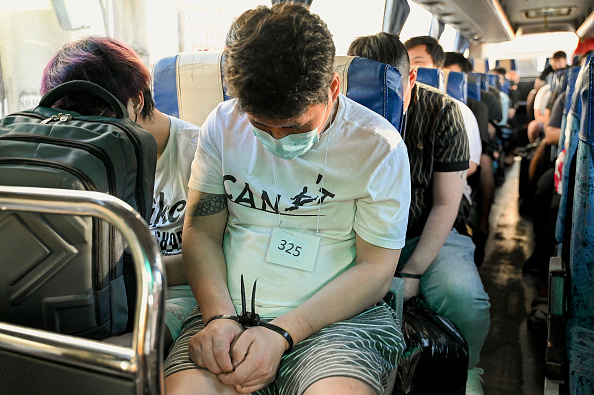 Des ressortissants chinois dans un bus avant leur expulsion après un raid sur une opération présumée de trafic sexuel et d'escroquerie en ligne à Pasay, le 14 décembre 2023. (Photo JAM STA ROSA/AFP via Getty Images)