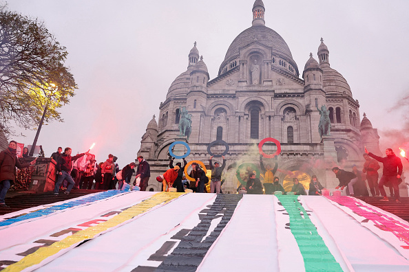 Des banderoles déployées sur les marches de la basilique du Sacré-Cœur pour attirer l'attention sur l'impact des Jeux olympiques de Paris 2024 sur les communautés à faible revenu et les mal-logés, à Paris, le 15 décembre 2023. (Photo THOMAS SAMSON/AFP via Getty Images)