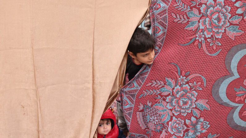 Des enfants palestiniens, déplacés par le bombardement israélien de Khan Younès, cherchent un abri à l'intérieur d'une tente agricole à Rafah, dans le sud de la bande de Gaza, le 21 décembre 2023, alors que les combats se poursuivent entre Israël et le groupe militant du Hamas. (Photo MOHAMMED ABED/AFP via Getty Images)