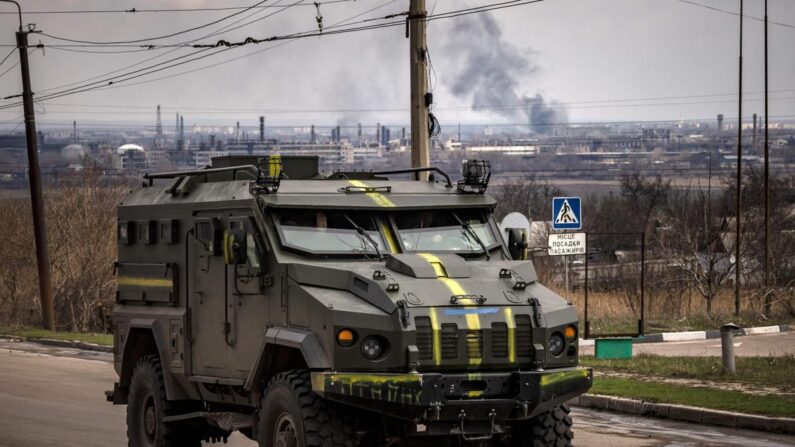 Un véhicule blindé de l'armée ukrainienne passe sur une route alors que de la fumée s'élève en arrière-plan dans la ville de Severodonetsk, dans la région du Donbass, en Ukraine, le 6 avril 2022. (Fadel Senna/AFP via Getty Images)