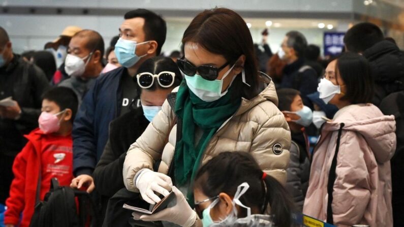 Une femme porte un masque de protection et des gants en attendant de passer le service d'immigration à l'aéroport de Pékin, le 1er février 2020. (Greg Baker/AFP via Getty Images)