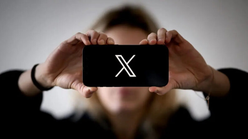 Une femme tient un smartphone affichant le logo du réseau social X (anciennement Twitter), à Nantes, dans l'ouest de la France, le 29 novembre 2023. (Loic Venance/AFP via Getty Images)
