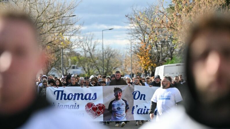 Des personnes défilent le 22 novembre 2023, à Romans-sur-Isere, derrière une banderole sur laquelle on peut lire "Thomas, dans nos cœurs à jamais, on t'aime". (OLIVIER CHASSIGNOLE/AFP via Getty Images)