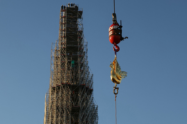 Le nouveau coq doré contenant des reliques est soulevé par une grue pour être installé au sommet de la flèche de la cathédrale Notre-Dame de Paris. (Photo THOMAS SAMSON/AFP via Getty Images)