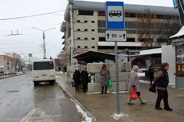 Des personnes attendent à un arrêt de bus protégé par des blocs de béton suite aux récents bombardements ukrainiens présumés à Belgorod, à la frontière de l'Ukraine, le 15 janvier 2024. (Photo STRINGER/AFP via Getty Images)