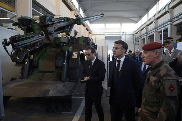 Emmanuel Macron et le ministre français des Armées Sébastien Lecornu inspectent un système d'artillerie automoteur Caesar lors d'une visite de la base navale de Cherbourg dans le cadre des vœux du président à l'armée française, le 19 janvier 2024. (CHRISTOPHE PETIT TESSON/POOL/AFP via Getty Images)