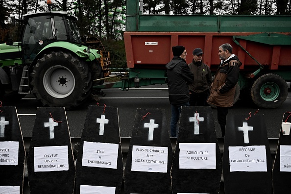 Des agriculteurs se tiennent près de faux cercueils lors d'une manifestation qui bloque la rocade de Bordeaux, le 24 janvier 2024. (PHILIPPE LOPEZ/AFP via Getty Images)