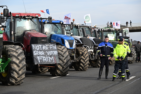 La police française se tient à côté de tracteurs alors que les agriculteurs français participent à un barrage routier sur l'autoroute A4 près de Jossigny, à l'est de Paris, le 29 janvier 2024 (BERTRAND GUAY/AFP via Getty Images)