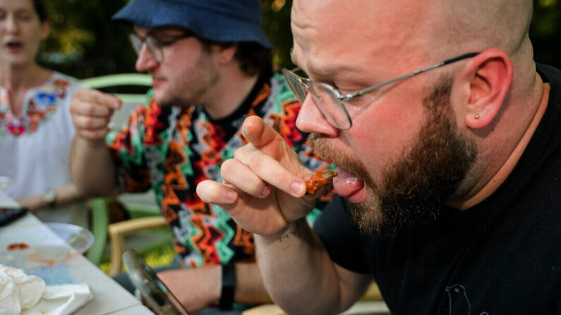 Un groupe d'amis mange des insectes frits à la poêle dans le cadre du défi Hot One's, à Hyattsville, dans le Maryland, le 4 juin 2021. (Chip Somodevilla/Getty Images)