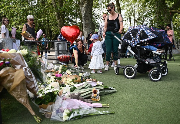 Des personnes déposent des fleurs et des bougies à la mémoire des victimes d'une attaque au couteau survenue dans le parc des Jardins de l'Europe à Annecy, le 8 juin 2023. (OLIVIER CHASSIGNOLE/AFP via Getty Images)